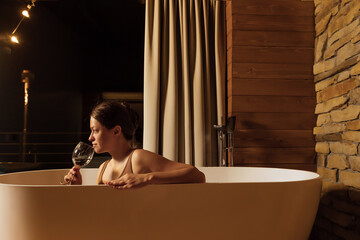 Relaxing in a modern bathtub with a glass of wine at night