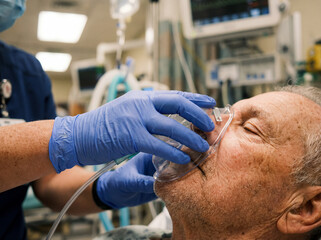 Medical hand putting oxygen mask on senior patient face hospital emergency breathing support healthcare assistance resuscitation life saving close up clinic treatment professional urgency breath sick 