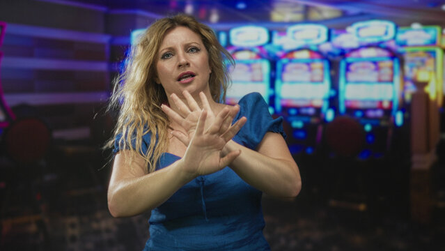 Woman pushing palms forward toward camera in studio with slot machines and neon lights, hands extended and hair moving from motion; rejection. - Powered by Adobe
