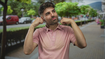 Fototapeta premium Man makes crying gesture with fists near eyes on a city street lined with trees and benches; sadness.