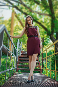 Elegant woman standing on outdoor metal stairs in summer park