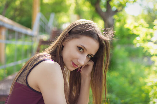 Young woman posing outdoors on sunny spring day with natural green background