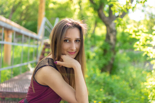 Young woman posing outdoors on sunny spring day with natural green background