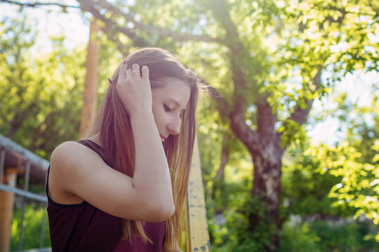 Young woman posing outdoors on sunny spring day with natural green background