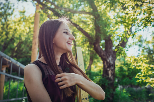 Young woman posing outdoors on sunny spring day with natural green background