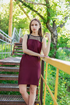 Elegant woman standing on outdoor metal stairs in summer park