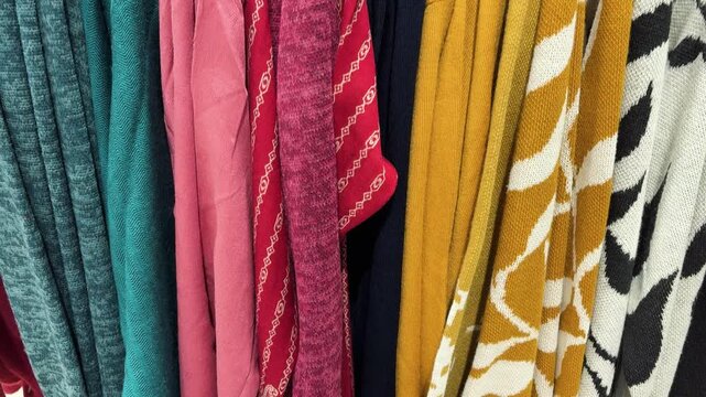 colorful winter sweaters displayed on rack in clothing retail store for sale