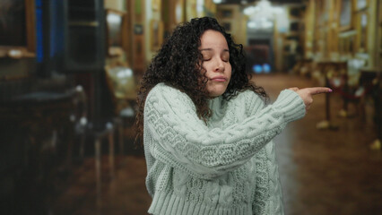 Young hispanic woman in a cozy sweater expresses emotion with a hand gesture inside an ornate...