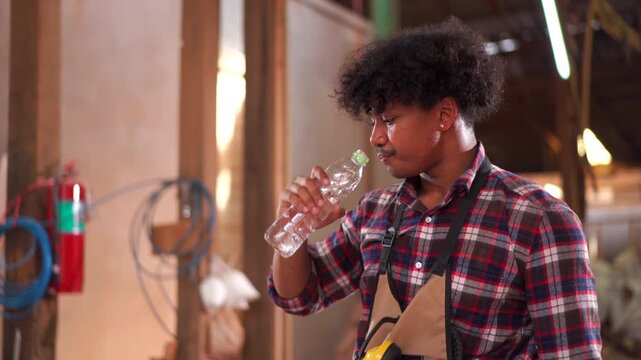Carpenter drinking water while taking a break in a woodworking factory.