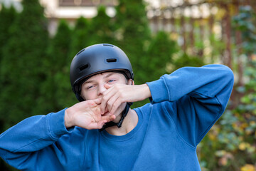 Excited young teenage boy in a safety helmet cheering or reacting enthusiastically with a joyful, exaggerated expression outdoors