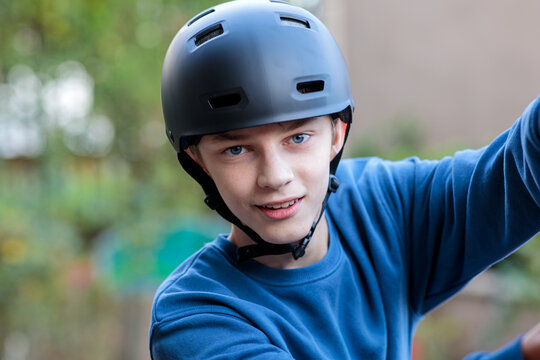 Close-up portrait of a happy young teenage boy in a black safety helmet, smiling confidently while engaging in an outdoor activity - Powered by Adobe
