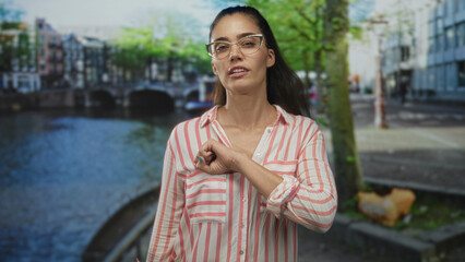 Woman with raised fist making a fist bump gesture on a street by a canal in amsterdam; solidarity friendship.
