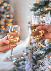 Man and woman with champagne in their hands near the Christmas tree. Selective focus.