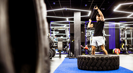 Man exercises with tire in modern gym during workout session