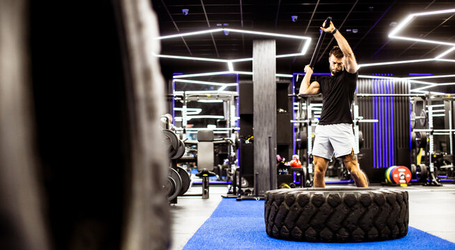 Man exercises with tire in modern gym during workout session