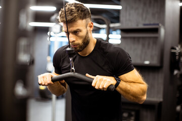 Focused man performing strength training at the gym in the evening