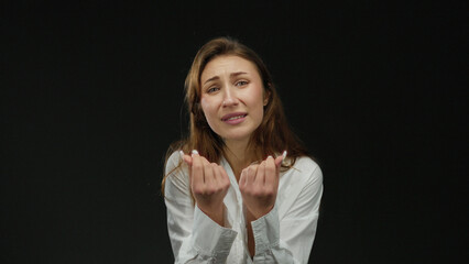 Fototapeta premium Woman expressing emotion with hands over isolated black background, wearing white shirt, conveying clear and impactful message with strong visual elements and intense focus.
