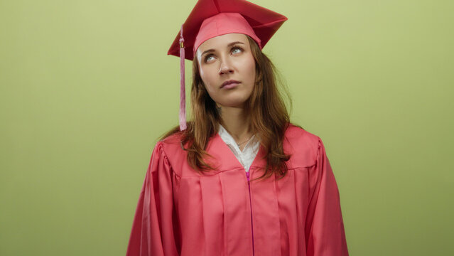 Woman wearing graduation gown stands isolated against yellow background looking tired and unmotivated after finishing her studies capturing the essence of student life fatigue.