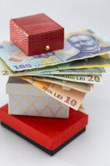 A stack of colorful Romanian Leu (RON) banknotes (100, 20, 10 Lei) piled on top of elegant gift boxes, symbolizing wealth, expenses, and luxury shopping