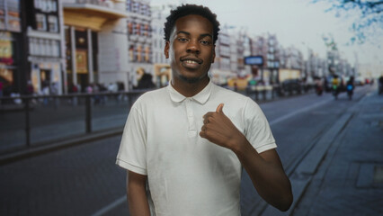 Man pointing finger to white polo shirt against blurred sidewalk and storefront building facades in...