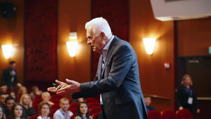 Mature man giving presentation to audience. Speaker talking about business, technology at conference. Public speaker addressing the audience, indoor. - Powered by Adobe