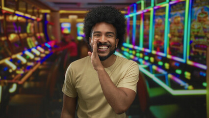 Smiling man in casino with vibrant slot machines creating lively atmosphere of joy and anticipation indoors under bright colorful lights