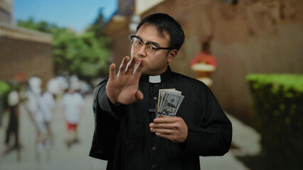 Man wearing clerical attire stands outdoors examining currency in a bustling urban street with blurred pedestrians and historic architecture in the background.