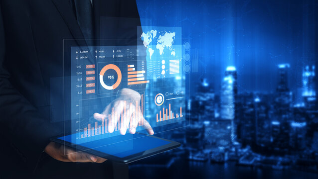 Business professional using a tablet to showcase interactive data visualizations over an urban night skyline, emphasizing technology and analytics in a modern city. Scalp
