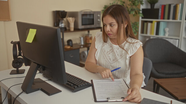 Woman pointing finger at document on desk in office while holding pen and reading a form; concentration. - Powered by Adobe