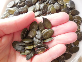 Seeds of a naked pumpkin in a woman's palm.