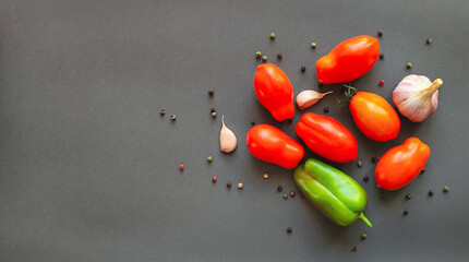 Composition of tomatoes, peppers and garlic on a gray background, top view with space for text