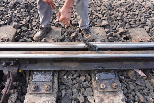 Railway Worker Performing Track Maintenance on Train Rails