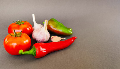 Composition of tomatoes, peppers and garlic on a gray background, top view with space for text