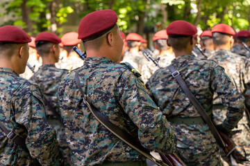 Fototapeta premium Young unrecognizable Asian soldiers in camouflage uniforms and red berets march solemnly in formation.