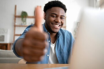 Young african american man giving thumbs up during video call at home desk