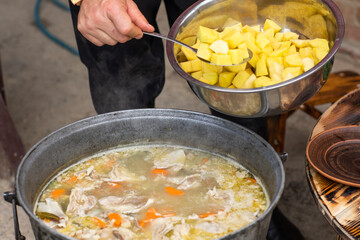 A man cooks traditional lamb soup in a cauldron over an outdoor fire in the Gagauzia autonomous region of Moldova. 