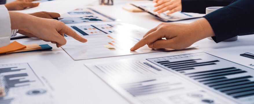 A collaborative business meeting scene showcasing diverse professionals engaging in analysis of charts and graphs, highlighting teamwork and communication in a modern office setting. SACTR