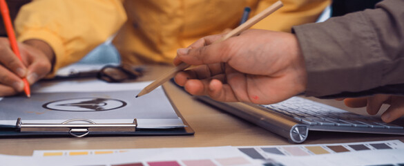 A vibrant collaborative workspace showcases diverse hands engaged in creative discussions. Color swatches and design sheets reflect an innovative atmosphere of teamwork and inspiration. SACTR
