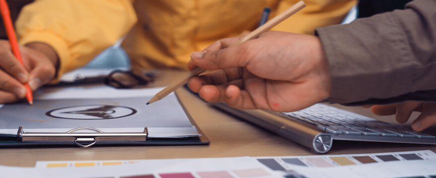A vibrant collaborative workspace showcases diverse hands engaged in creative discussions. Color swatches and design sheets reflect an innovative atmosphere of teamwork and inspiration. SACTR