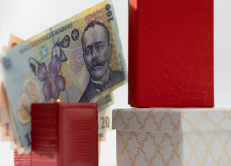 romanian leu banknotes (100 and 20) with the portrait of scientist aurel vlaicu next to elegant red and gold gift boxes, symbolizing shopping, luxury, and holiday expenses