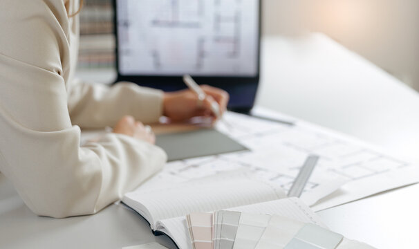 Female interior designer working on architectural plans in modern office, choosing materials and color for decorations. - Powered by Adobe
