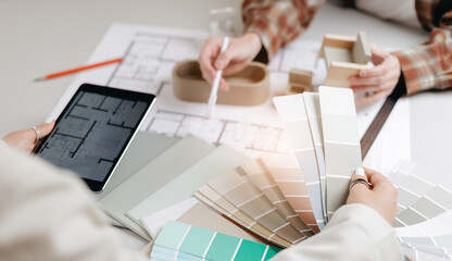 Interior designer with woman client selecting color swatches and reviewing floor plans