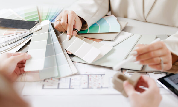 Color swatches and floor plan review by young caucasian women designers. Concept presentation of design interior for client.