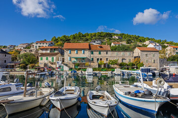 Obraz premium Coastal Harbor Village With Stone Buildings, Boats, And Calm Blue Water Reflections