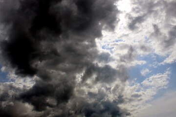 Background of blue bright sky with dark clouds.