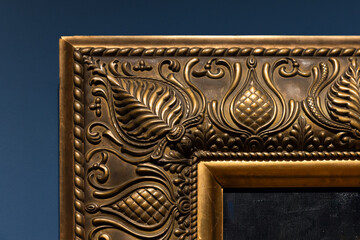 Close-up of an ornate gilded frame corner, featuring scrolling leaves and floral motifs