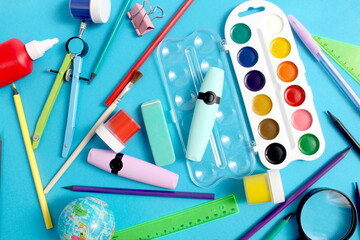 Lots of school supplies lie on a blue background.