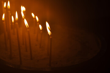 Several lit prayer candles glowing in the dark