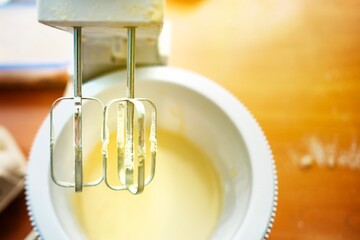 Mixer whisks raised over bowl with dough traces after finishing baking preparation