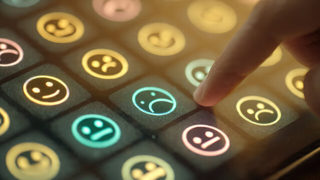 A finger selects a sad emoji on a glowing digital feedback screen, surrounded by other emotion icons for user sentiment input.